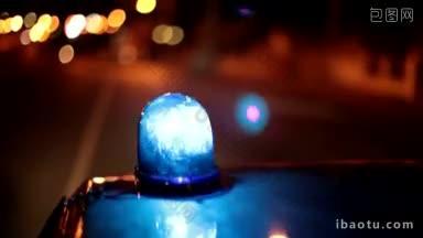 一辆警车的车顶上<strong>亮</strong>着<strong>蓝色</strong>的应急灯，行驶在夜城的街道上